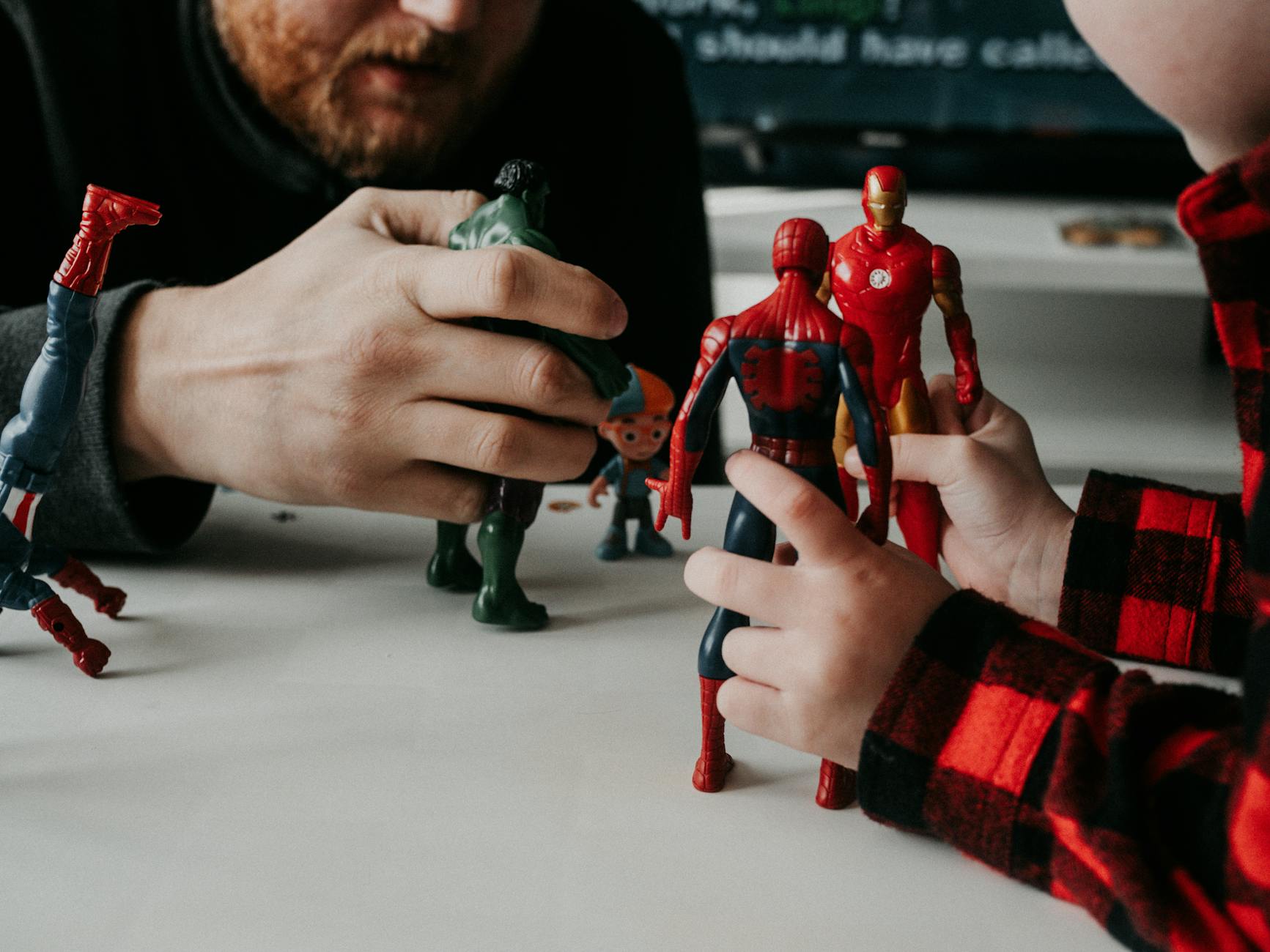 Action Figure — A father and son bond while playing with superhero action figures indoors.
