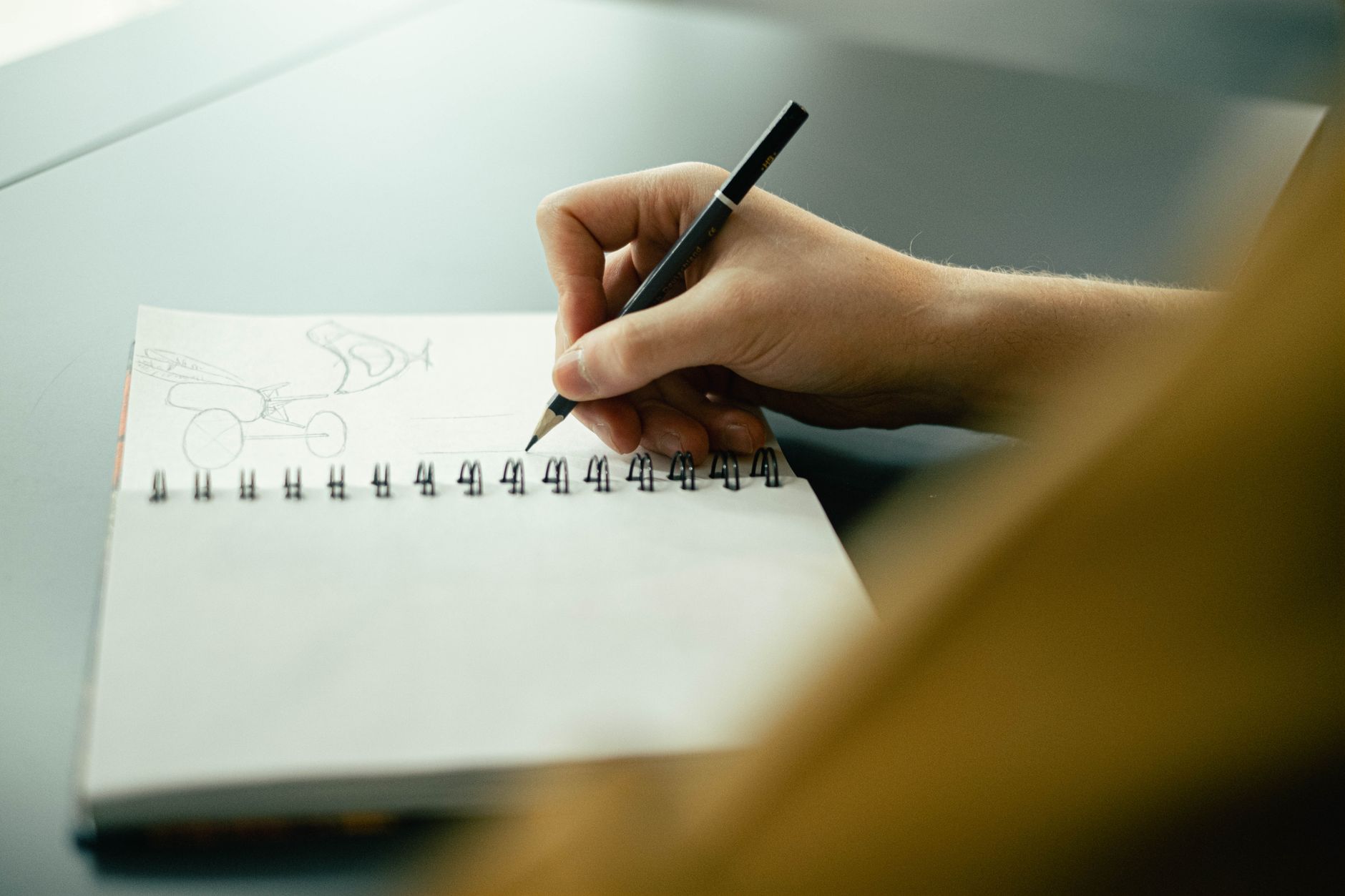Animation Idea — Hand sketching in a notebook with a pencil, focusing on creativity and planning.