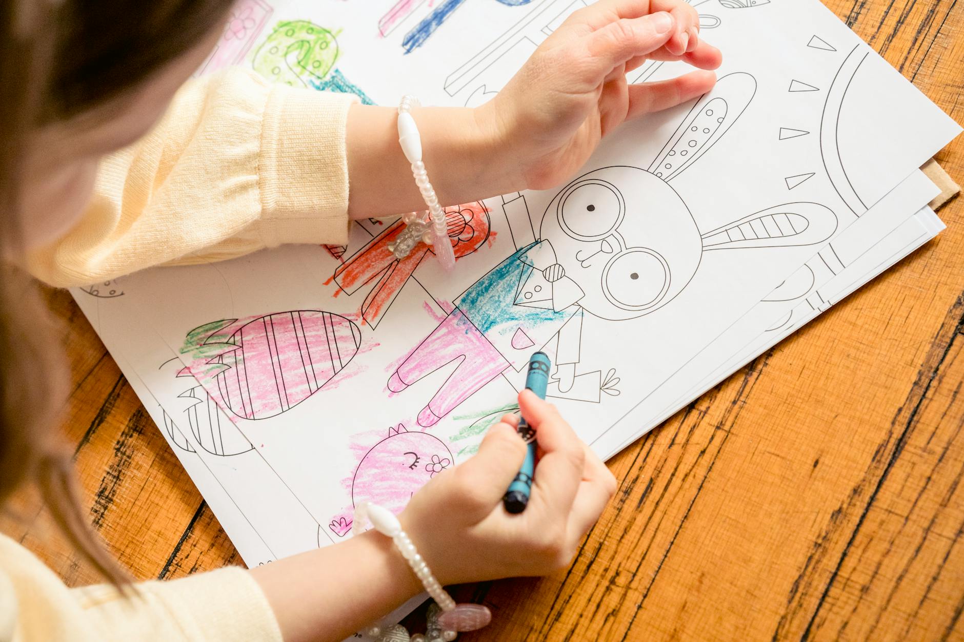 Coloring Page — From above of crop unrecognizable girl in casual clothes drawing in coloring book in daylight