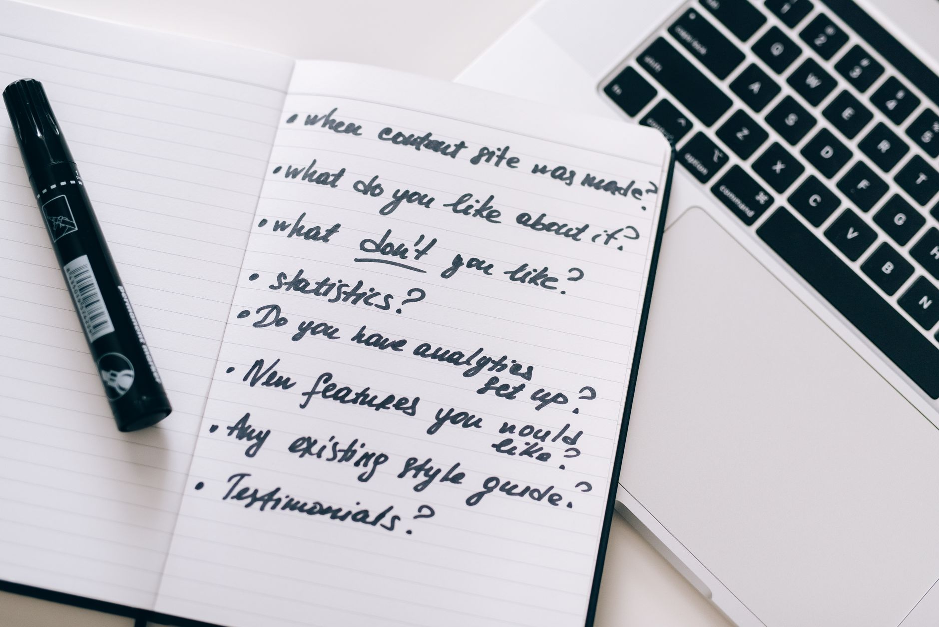 Close-up of a notebook with handwritten notes next to a laptop