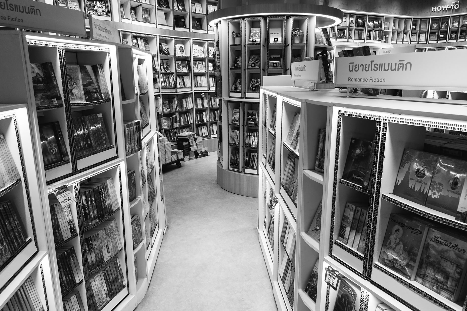 Fanfic — Monochrome view of a bookstore s interior with various bookshelves and romance fiction section.