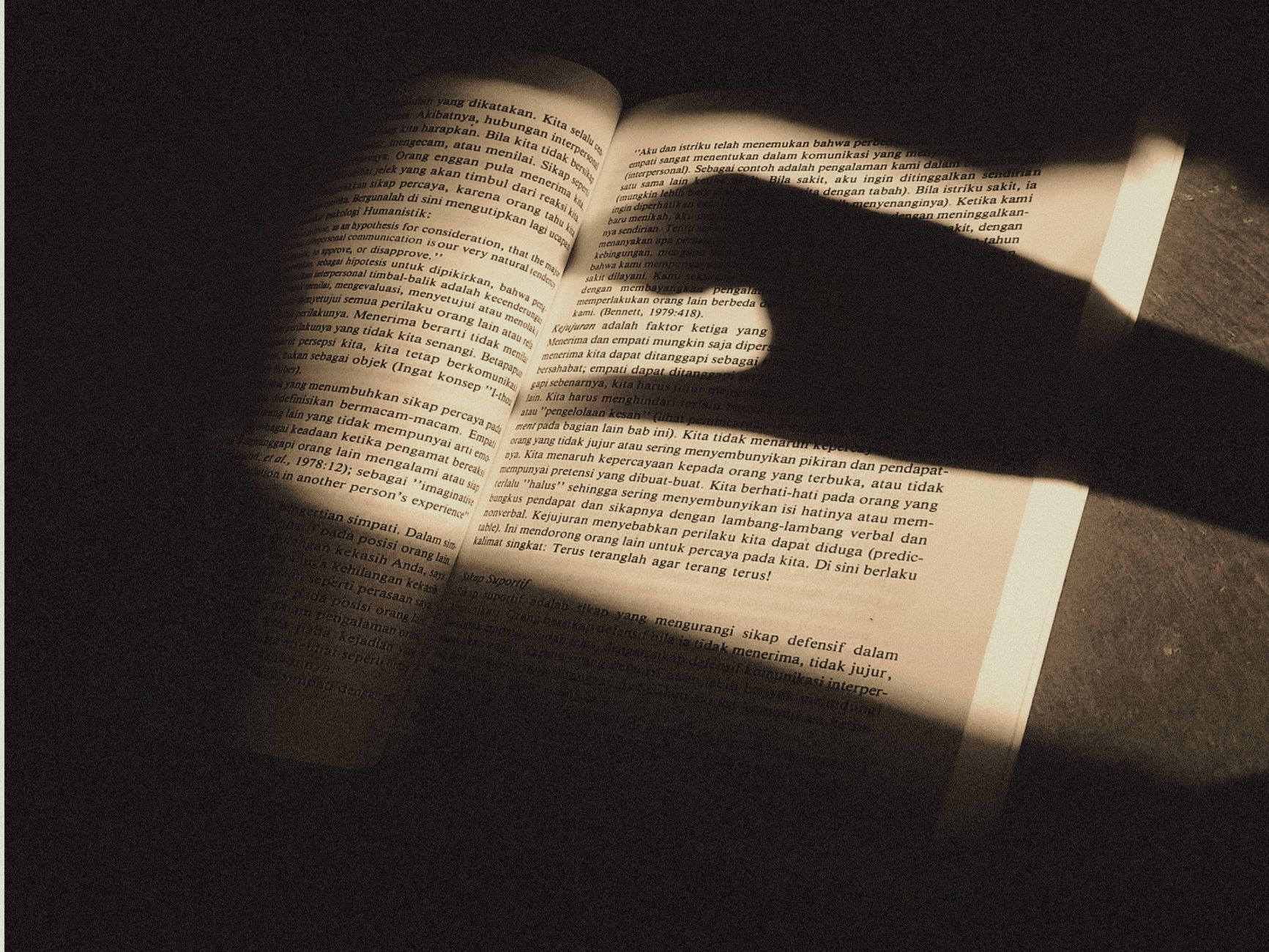 Fanfic — An open book with text illuminated by dramatic shadows, creating an intriguing visual effect.