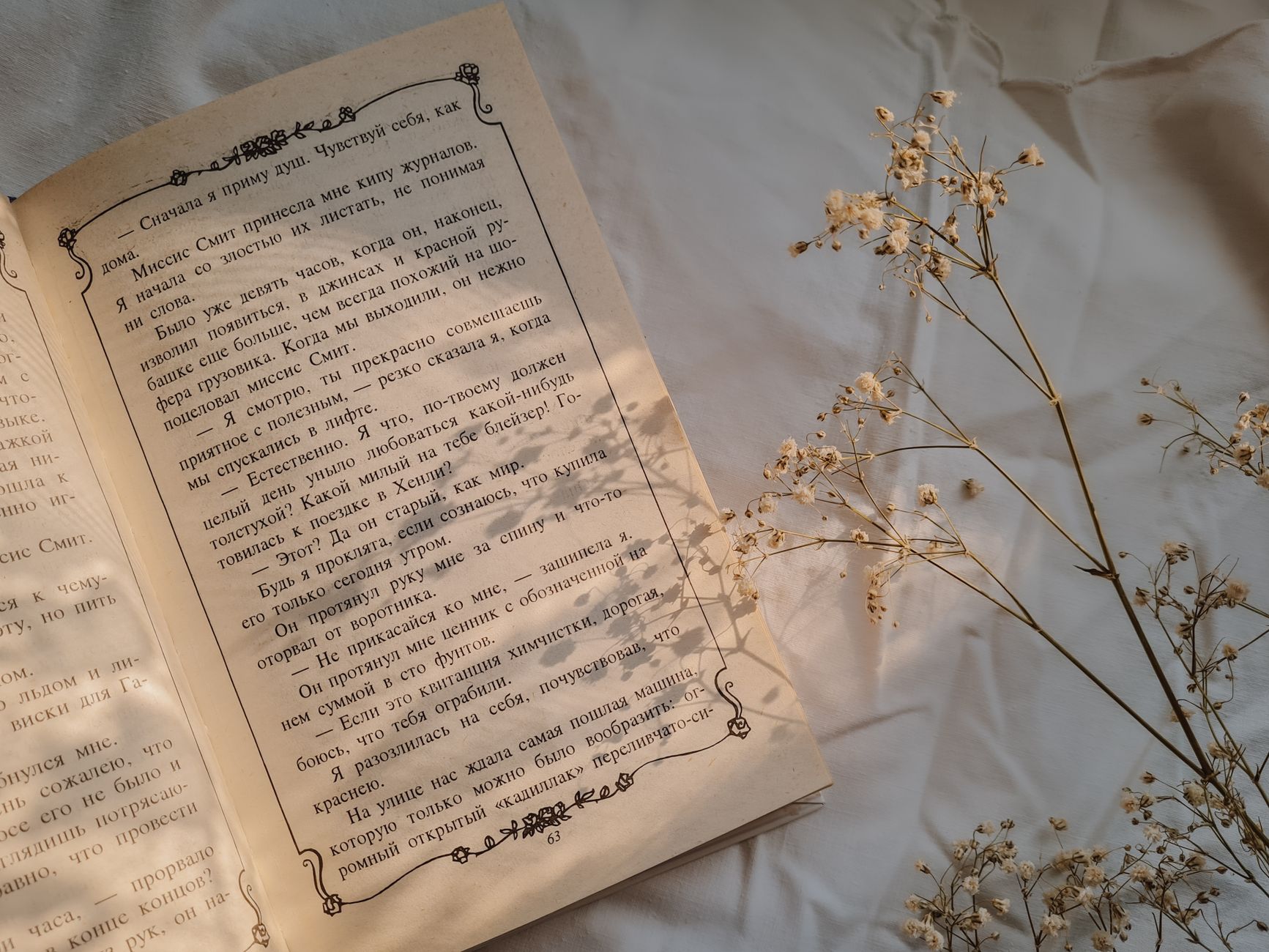 Fanfic — Open book on a soft bedsheet with gypsophila flowers gently placed beside it.