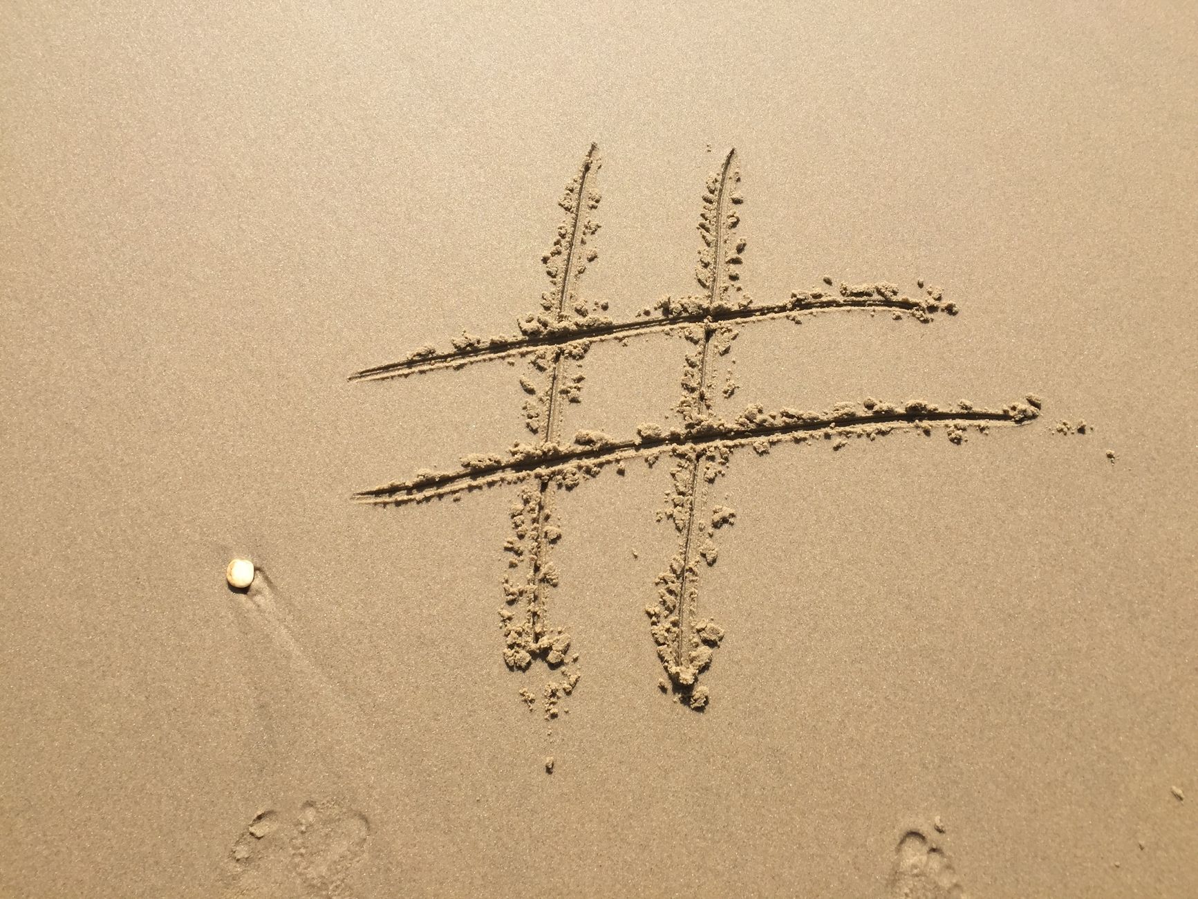 Hashtag symbol drawn on sandy beach ideal for social content