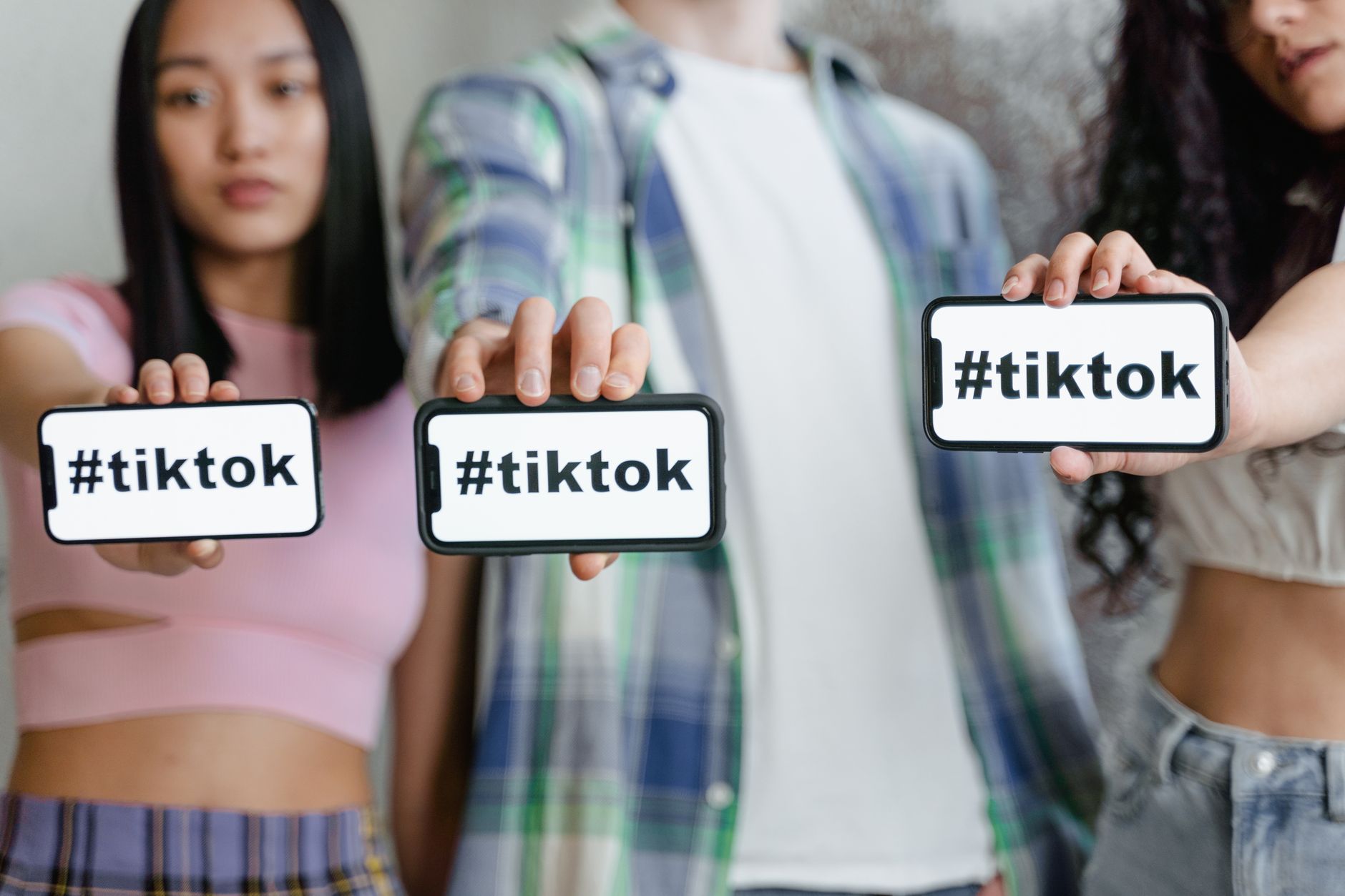 Young adults holding smartphones showing TikTok and hashtag theme