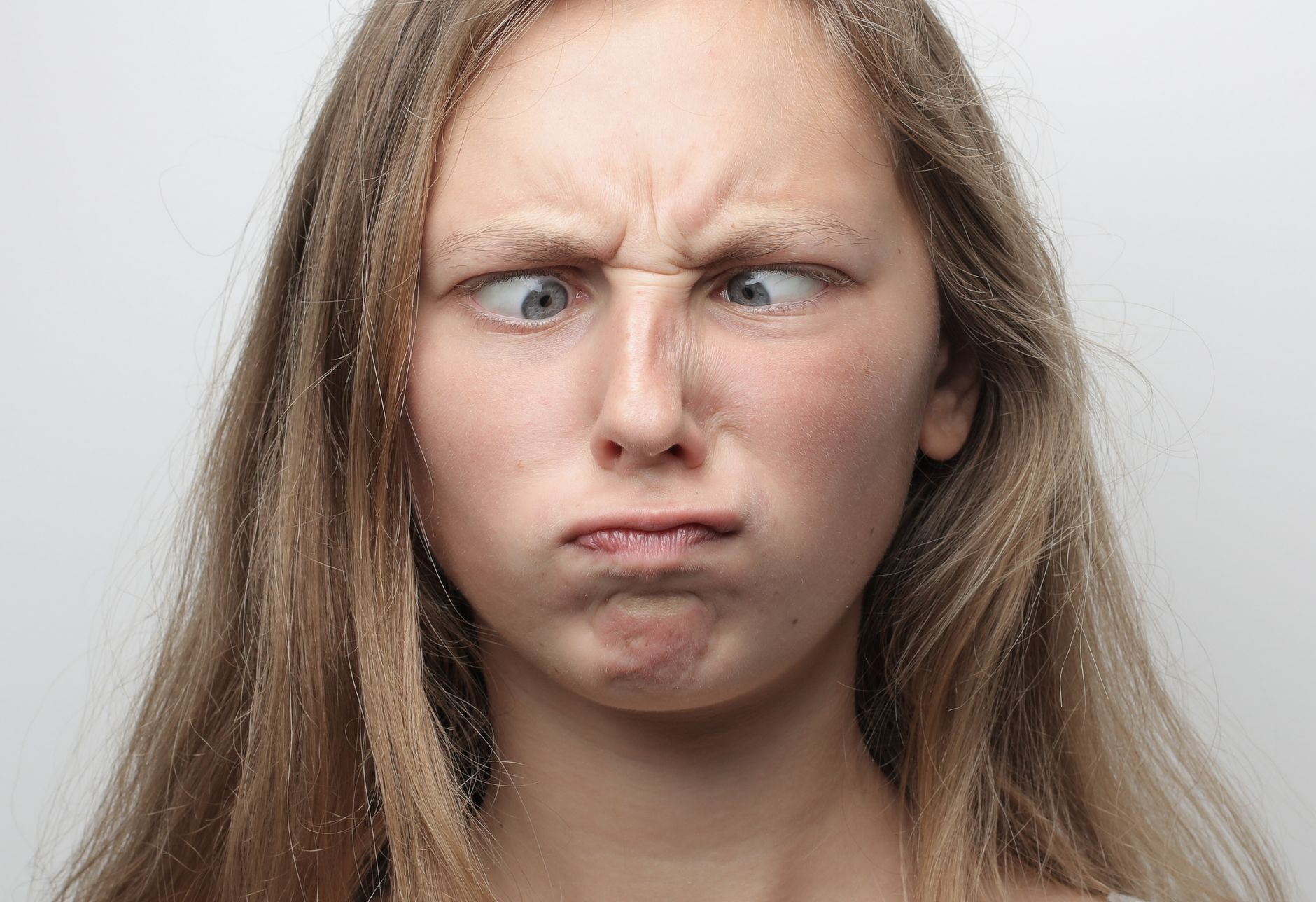 Close-up portrait of a girl with crossed eyes and a funny face indoors.