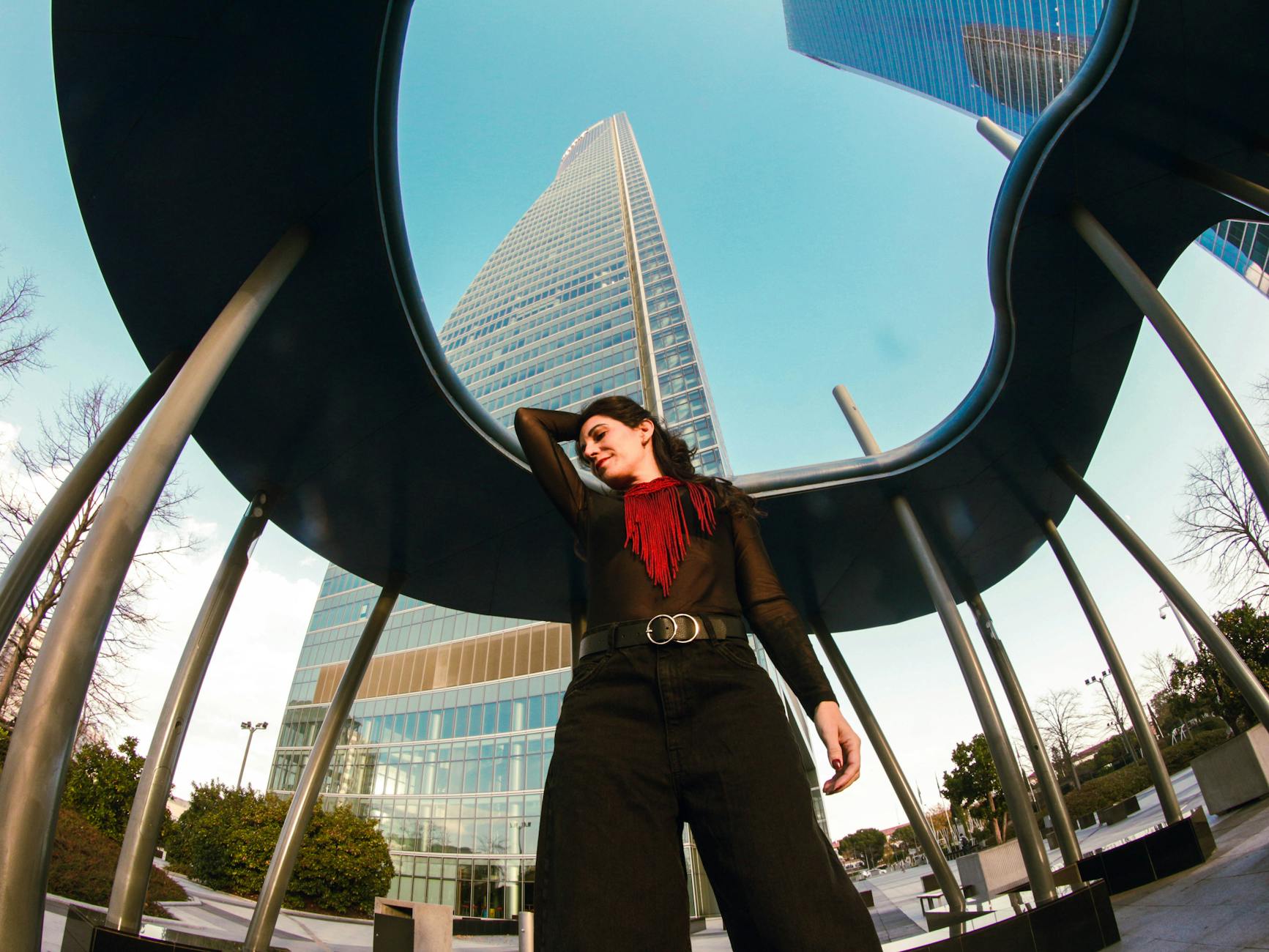 Outfit — Stylish woman poses confidently in a modern Madrid urban environment with skyscrapers.