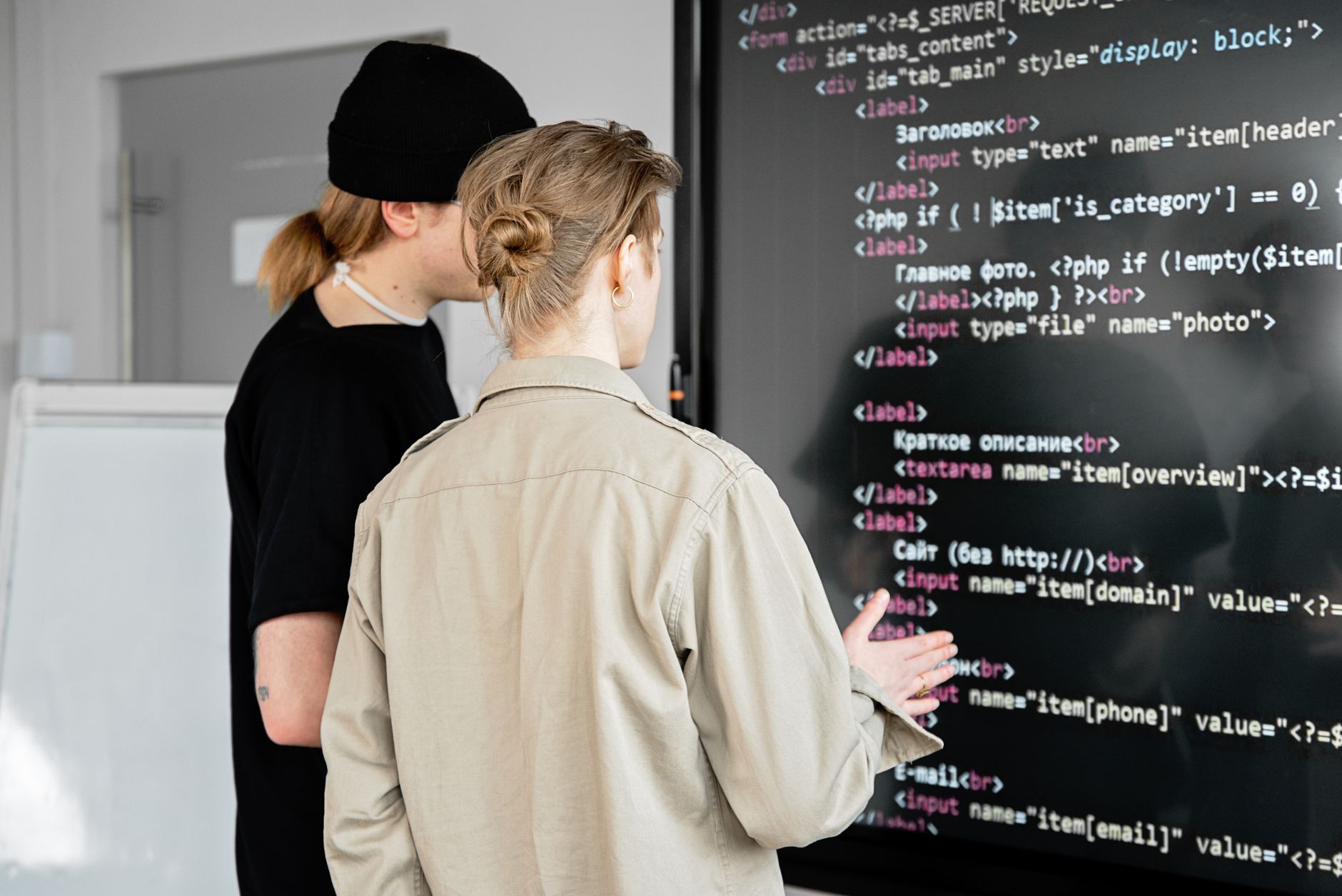 Pair Programmer, Coding Assistant, For Developers, Ship Code Faster With, Progr — Two developers examining code on a large screen in a mode