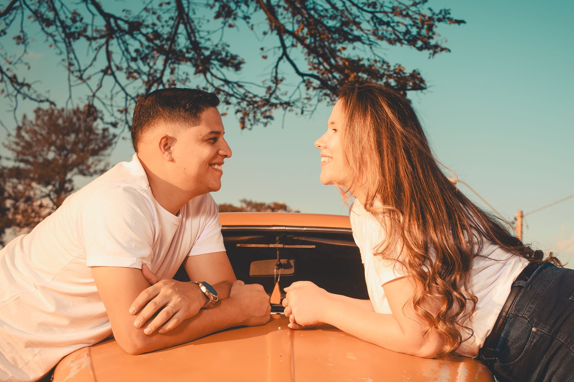 Pickup Line, Funny Pickup Lines, Smooth Pickup Lines, Pickup Line — A couple shares a joyful moment on a car hood during sunset, exuding l