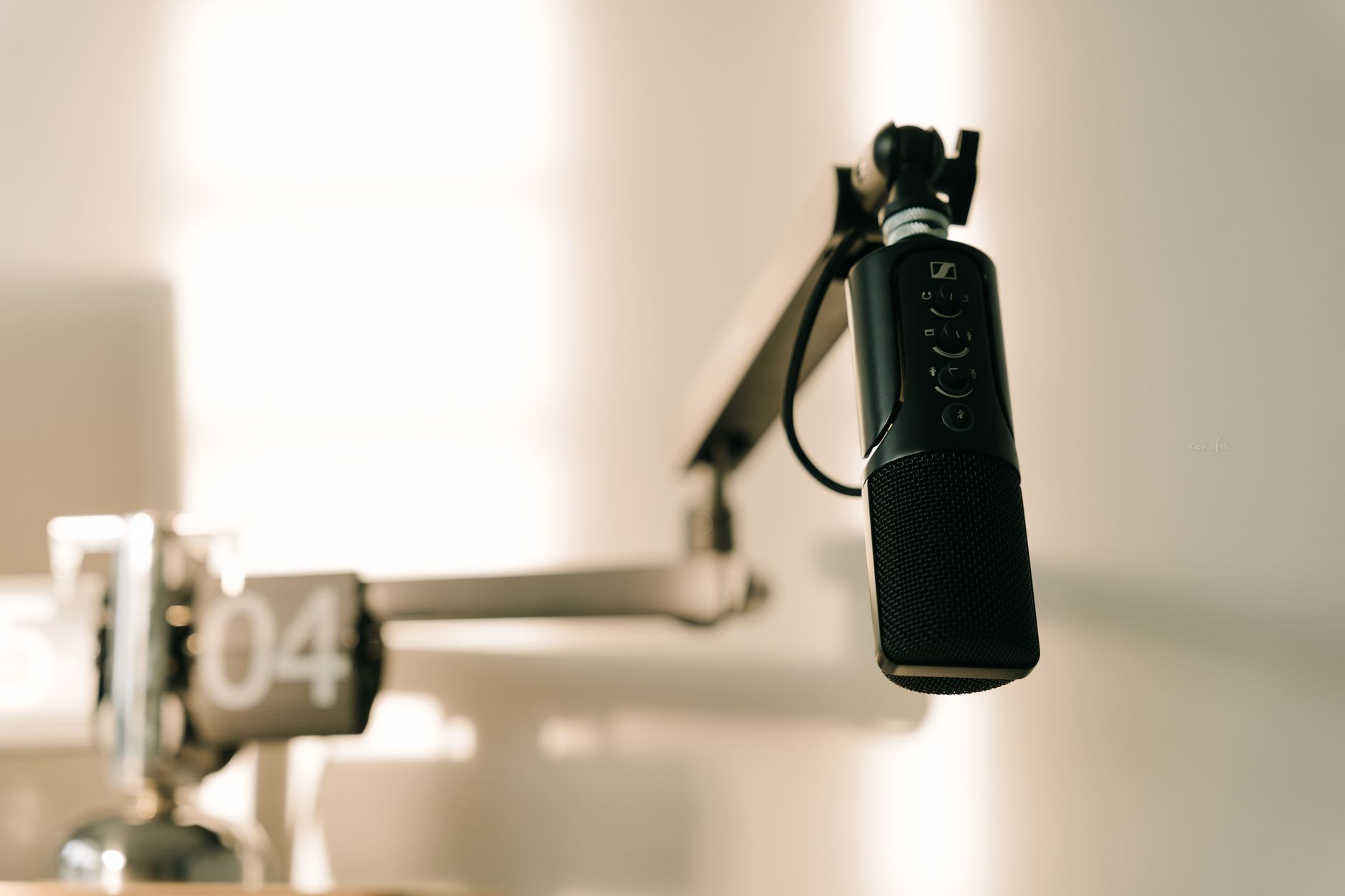 Podcast — A sleek professional microphone on a boom arm in a minimalist studio.