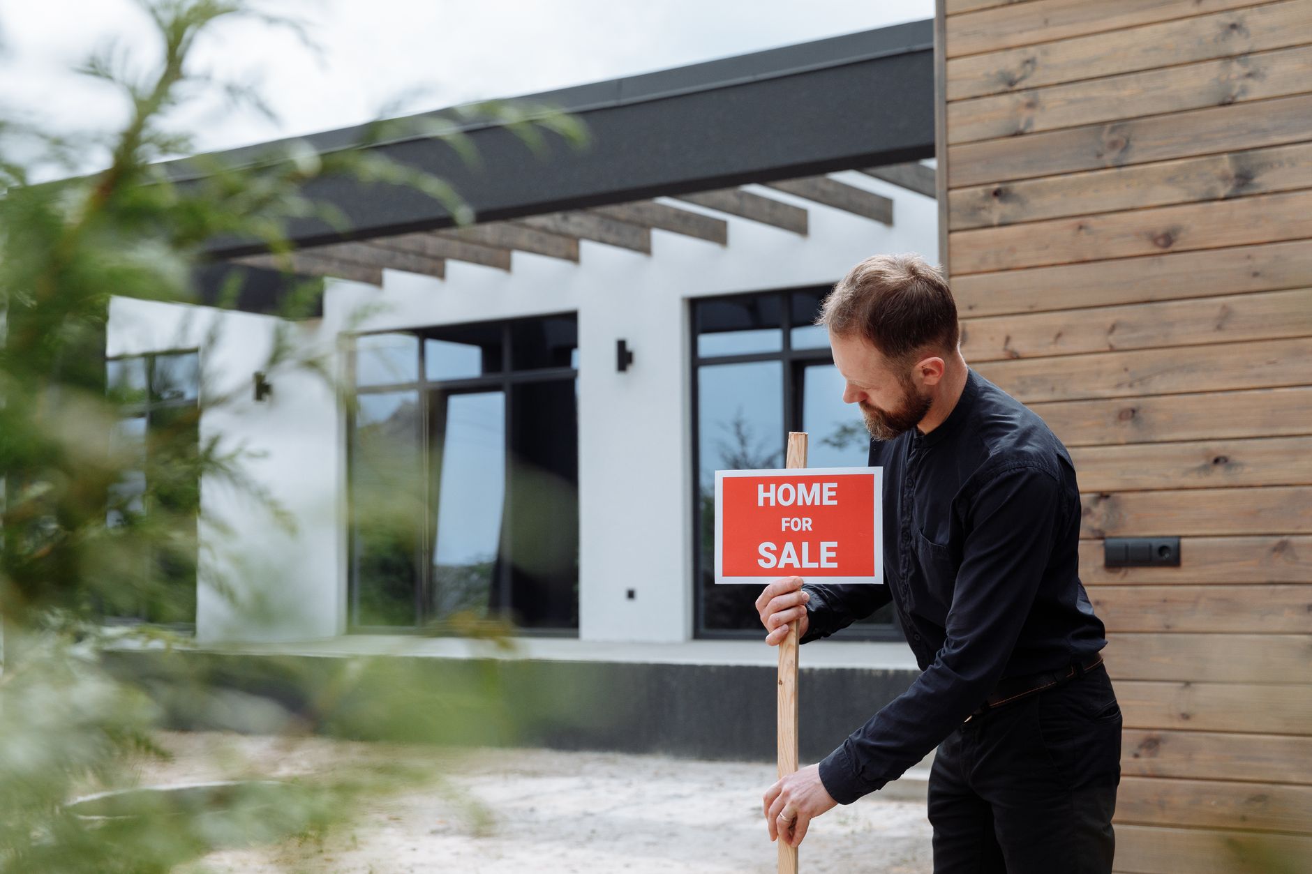 Real Estate Tools, Property Description, Real Estate Market Analysis, Listing — Man placing a home for sale sign outside a modern house f