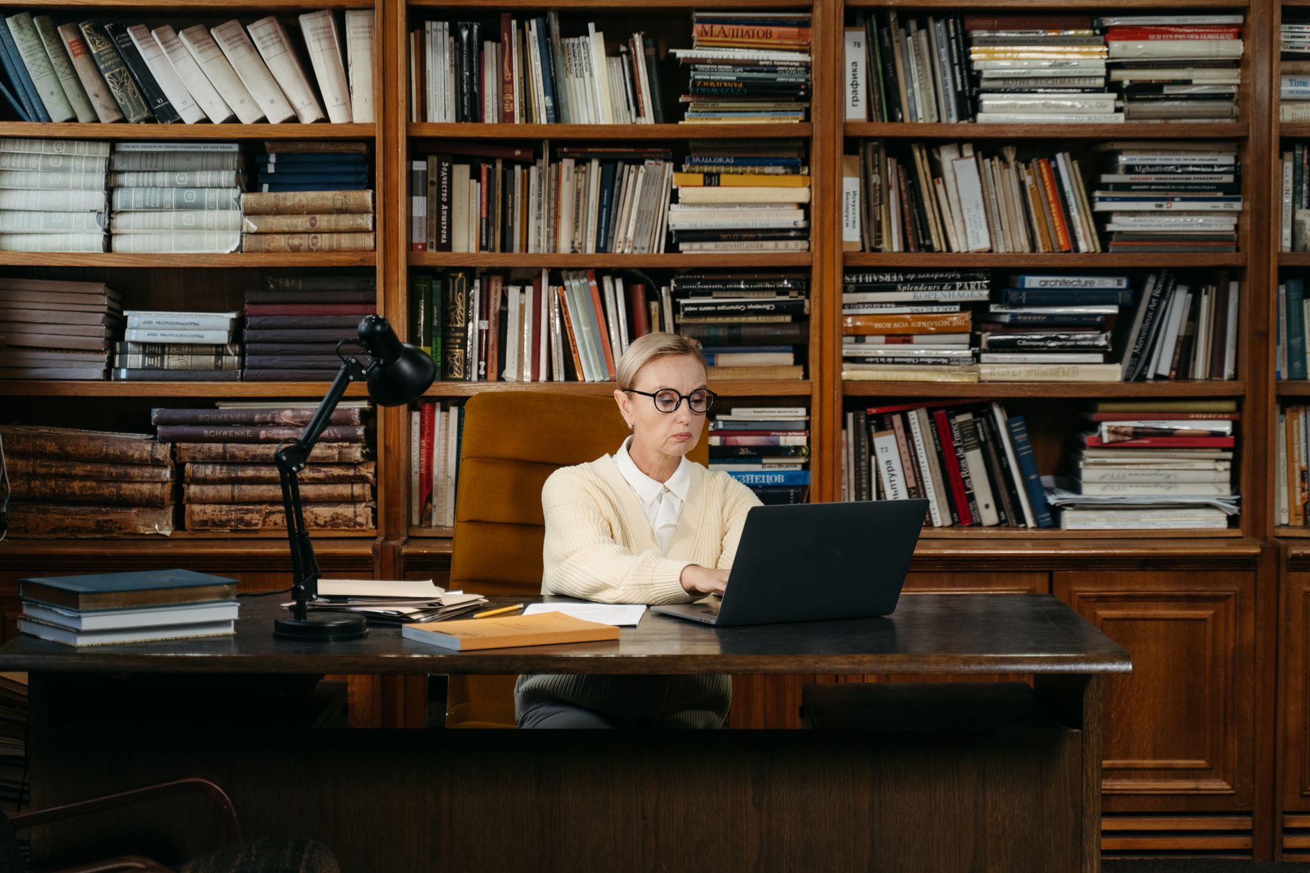 Research Assistant, For Academic Research, Powered Research, Literature Review, — Woman in a yellow sweater working on a laptop amidst book
