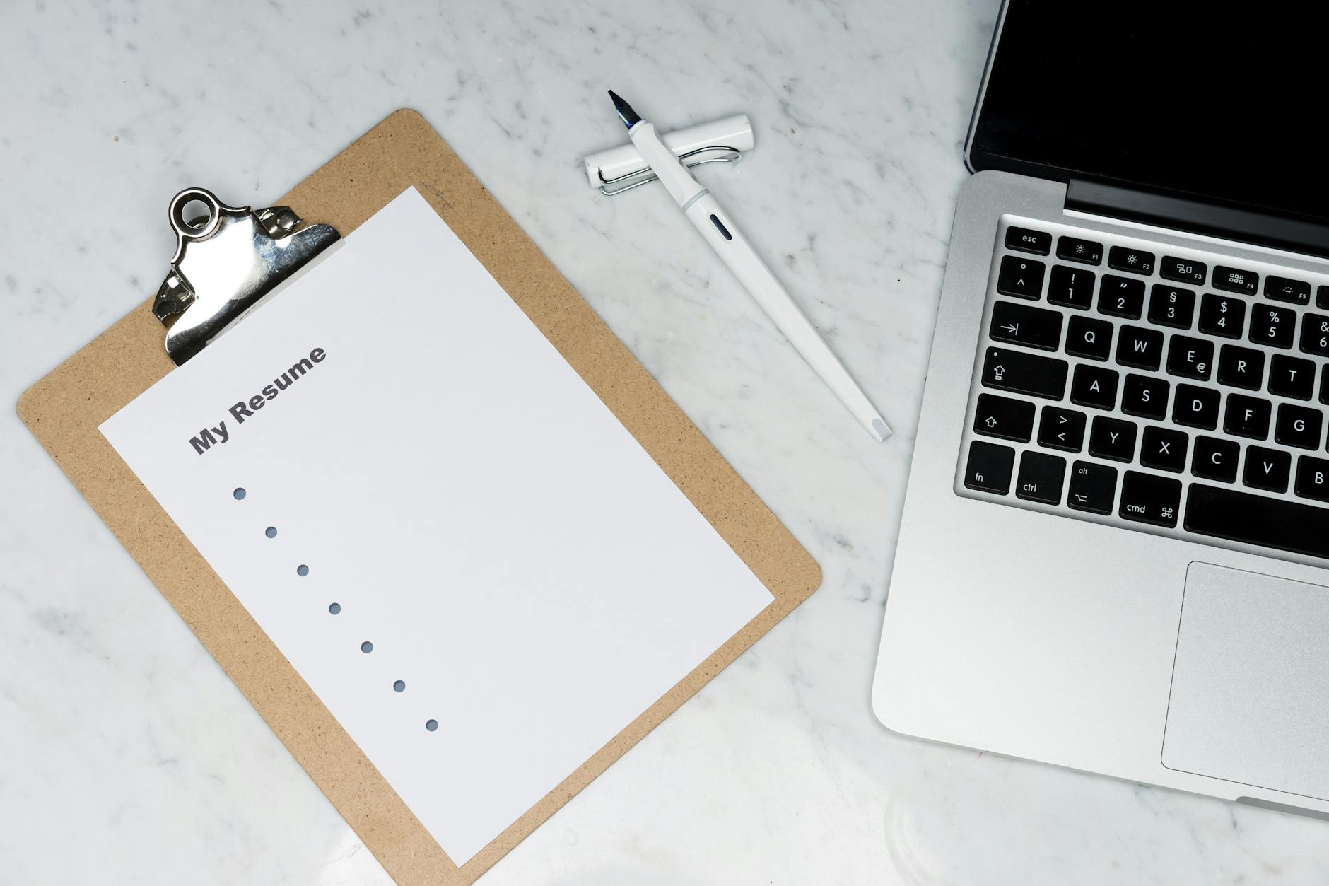 Resume Builder, ATS-Optimized Resume, Resume, ATS-Friendly Resume, Resume Writ — A clipboard with a resume beside a pen and laptop on a ma