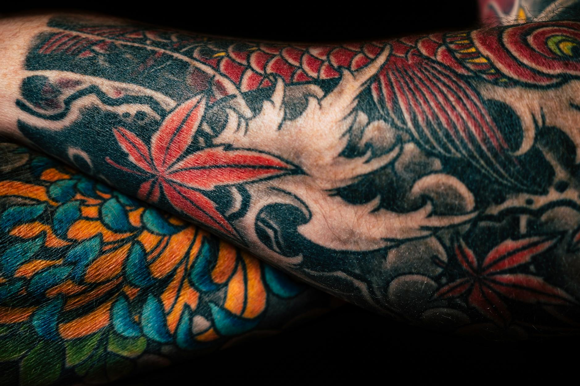Tattoo — Detailed close-up of colorful sleeve tattoos featuring floral and abstract designs, showcasing artistic creativity.