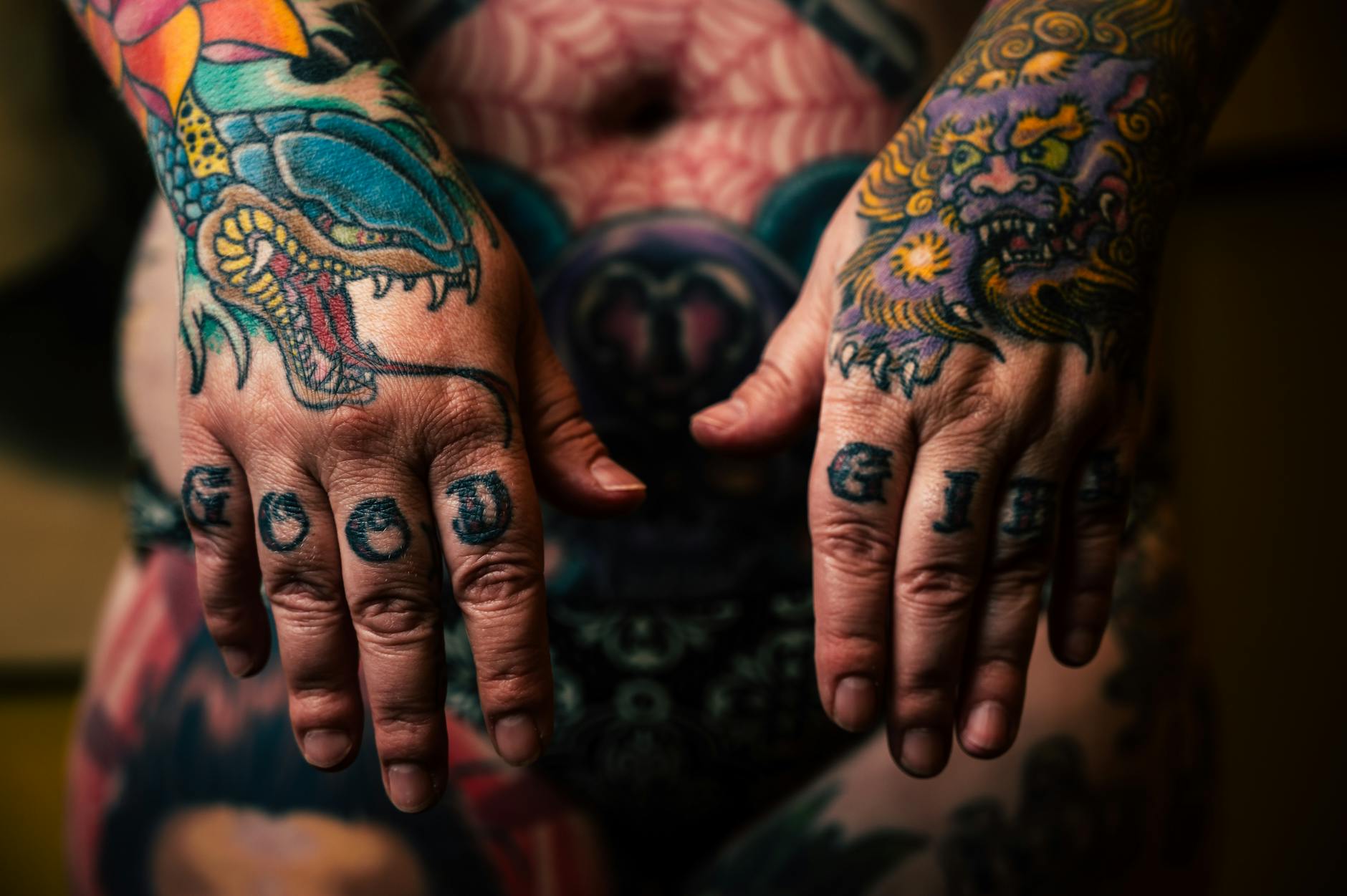 Tattoo — Close-up of vibrant tattooed hands with detailed dragon and mythical designs.