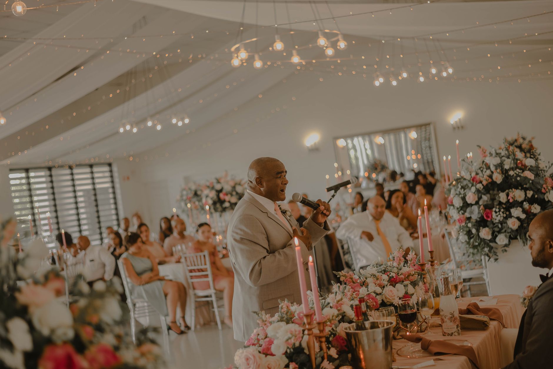 Wedding Speech Writer, Best Man Speech, Maid Of Honor Speech, Wedding Toast — A man gives a speech at a wedding reception surrounded by gu