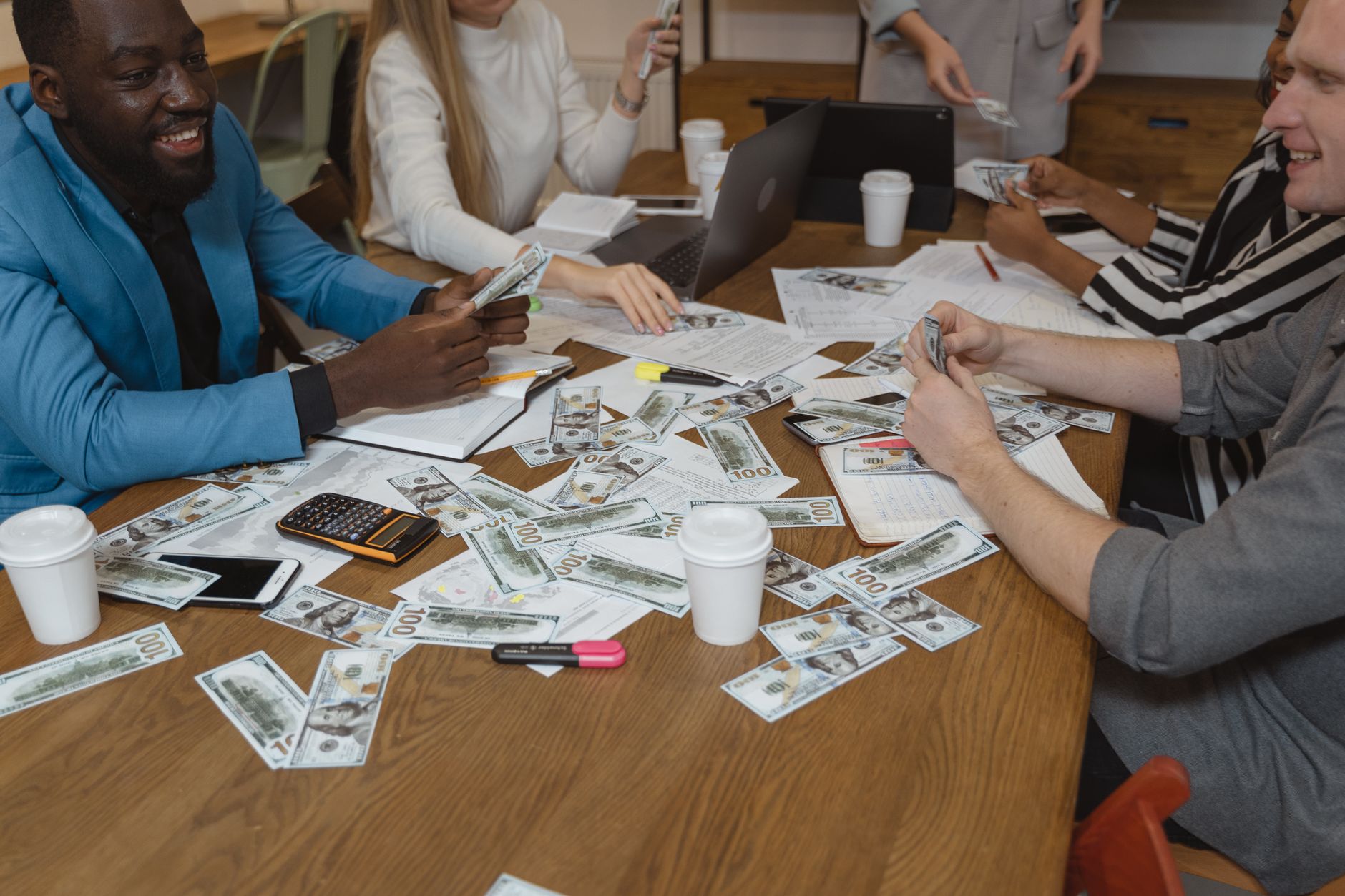 Best For Finance — Diverse team in a business meeting discussing strategies with currency on the table.