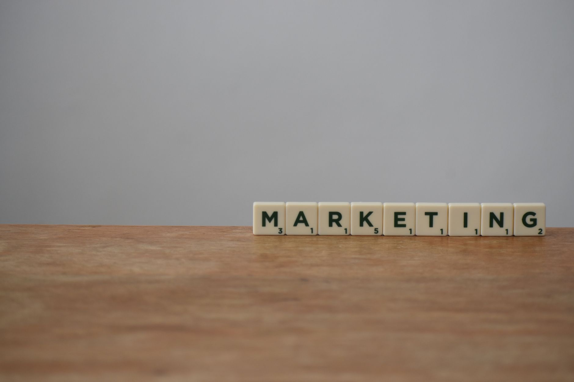 Best For Marketing — Scrabble tiles spelling MARKETING on a wooden table with a neutral background.