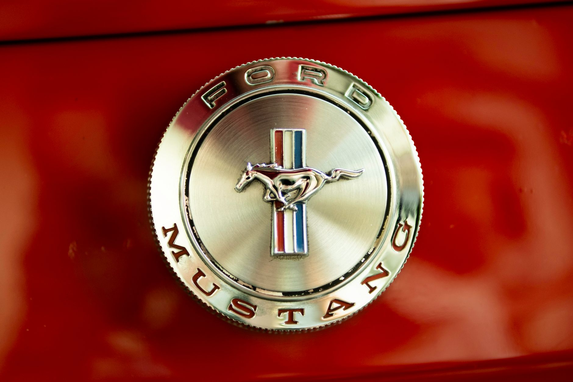 Best To Generate Logo — Close-up of a classic Ford Mustang emblem on a red background, showcasing vintage automotive design.