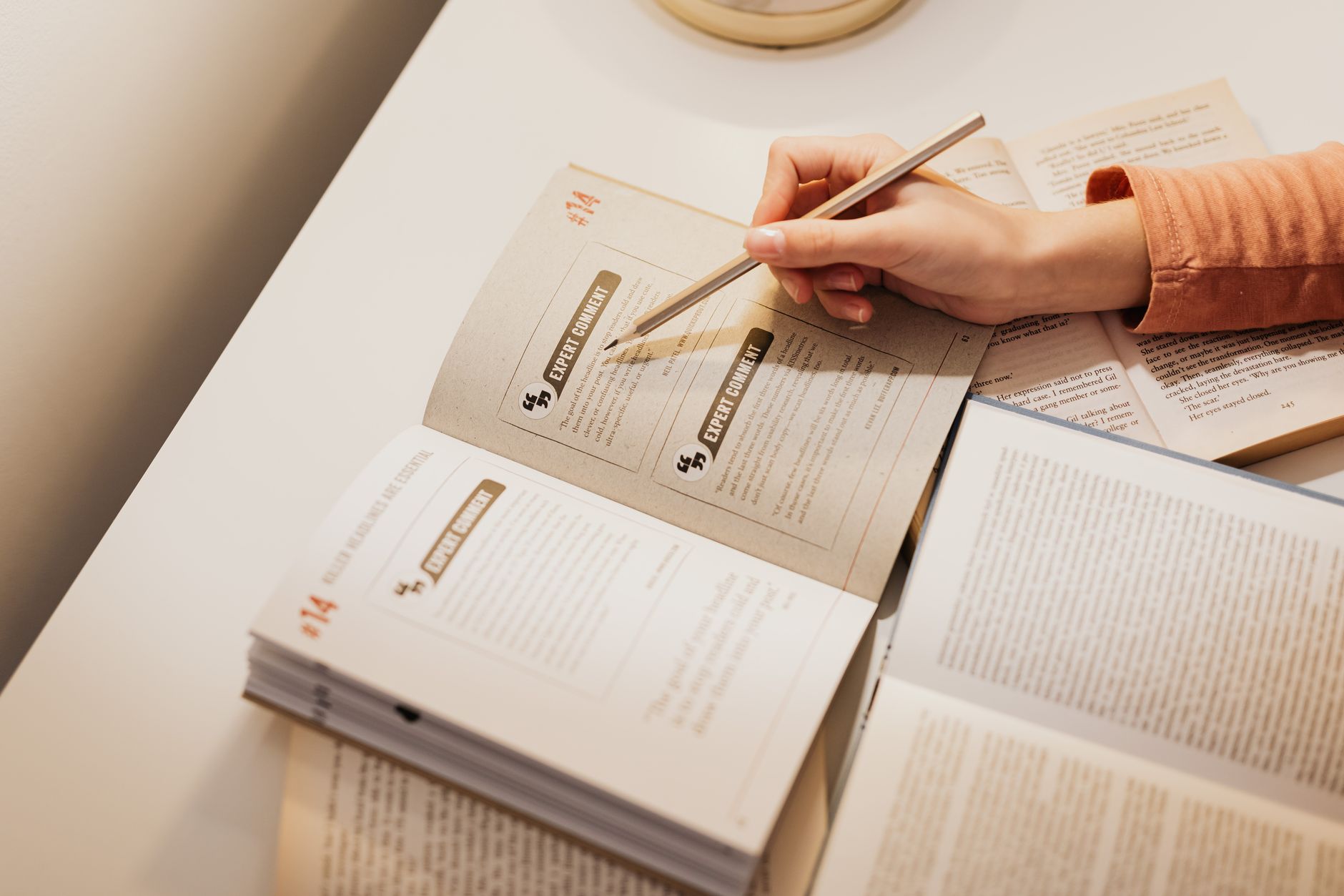 Study Guide — A woman using a pencil to annotate books while studying at a desk.